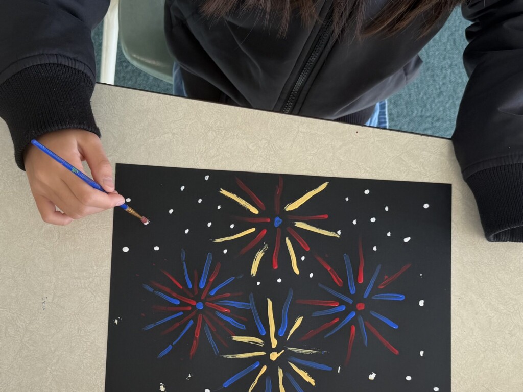 Child painting a colorful fireworks scene as an art project