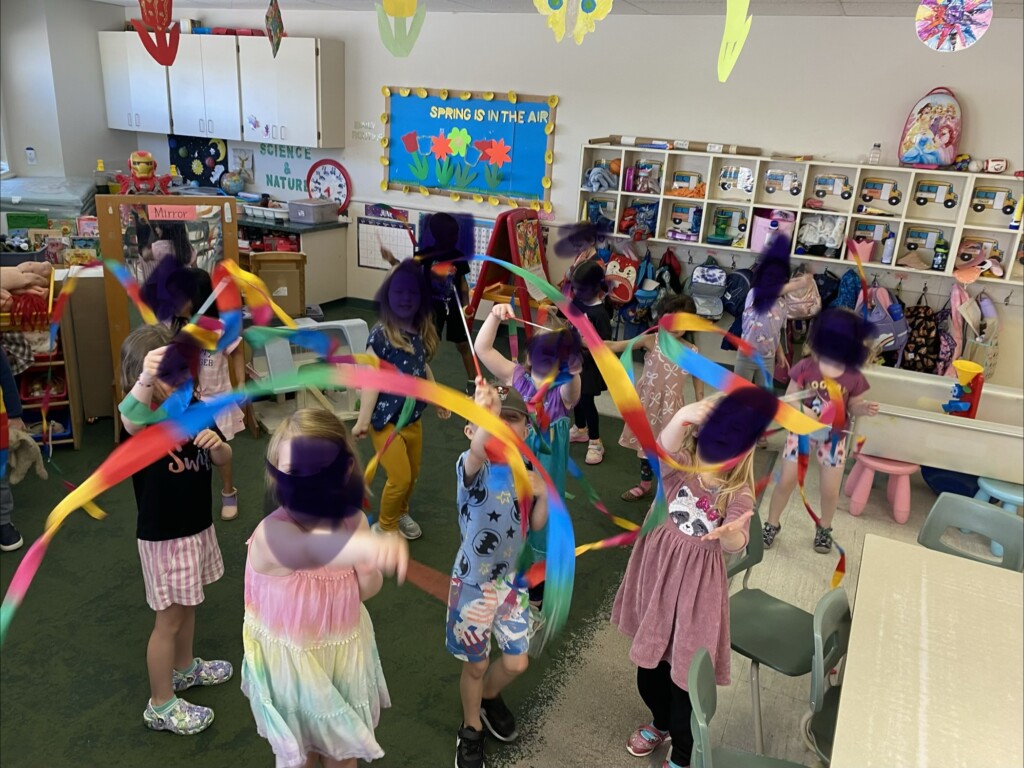Children dancing with colorful ribbon wands in the classroom